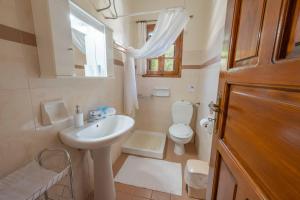 La salle de bains blanche est pourvue d'un lavabo et de toilettes. dans l'établissement House of Dimitra, à Gaios