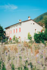 biały budynek z czerwonymi oknami i polem kwiatów w obiekcie B&B Al Giardino dei Laghi w mieście Revine Lago