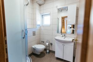 a white bathroom with a toilet and a sink at Apartment Stari Pazar in Konjic +5 photos