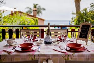 - une table avec des assiettes rouges, des verres et une bouteille de vin dans l'établissement Ascheri Country House - Grimaldi, Ventimiglia, à Vintimille