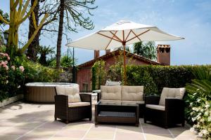 une terrasse avec une table, des chaises et un parasol dans l'établissement Ascheri Country House - Grimaldi, Ventimiglia, à Vintimille