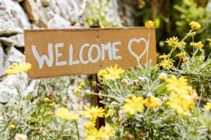 un cartel de bienvenida en un jardín con flores amarillas en Ascheri Country House - Grimaldi, Ventimiglia, en Ventimiglia