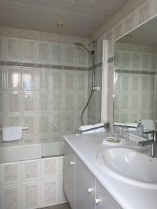 a white bathroom with a sink and a mirror at Hôtel de la Pointe du Grouin in Cancale