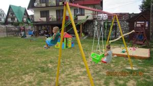 dos niños jugando en un columpio en un patio en DW U Wajdy, en Białka Tatrzanska