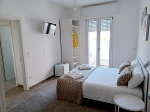 a white bedroom with a bed and a table at House Salento Central Rooms in Torre San Giovanni Ugento
