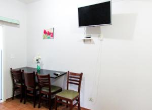 a dining room table with chairs and a television on the wall at Apto c Wi-Fi e lazer na Praia de Tabatinga SP in Caraguatatuba