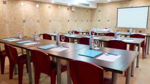 una sala de conferencias con mesas, sillas y una pantalla blanca en Sumus Hotel Stella & Spa 4*Superior en Pineda de Mar