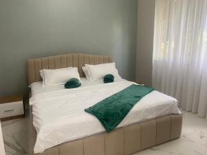 duże łóżko z białą pościelą i zielonymi poduszkami w obiekcie OrAnge villa w mieście Gonio