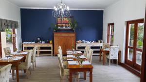 ein Esszimmer mit blauen Wänden, Holztischen und Stühlen in der Unterkunft Lavender Manor Guest Lodge in Hermanus