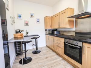 uma cozinha com armários de madeira e bancadas pretas em Aryelle House em Kendal