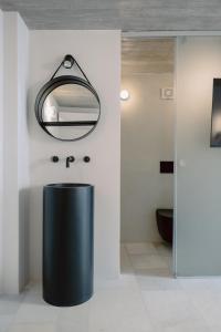 a bathroom with a black trash can and a mirror at Domino Syros by SV in Ermoupoli