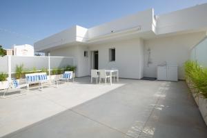Ein weißes Haus mit einer Terrasse mit Stühlen und Tischen in der Unterkunft Residence BLANCO GARDEN 1 a 100 mt dalla spiaggia di Posto Vecchio Marina di Pescoluse in Marina di Pescoluse