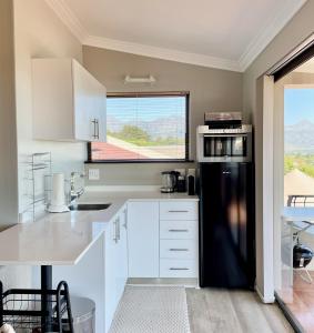 una cucina con armadietti bianchi e frigorifero nero di Dream Views a Somerset West