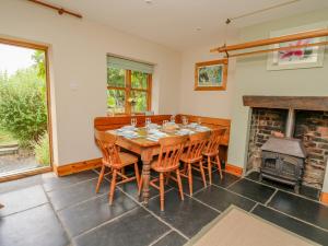 a dining room with a table and chairs and a fireplace at Byrdir Cottage in Llanwrthwl