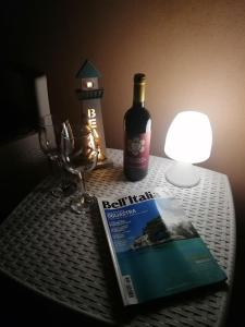 - un livre, une bouteille de vin et une lampe sur une table dans l'établissement Il Faro d'Ogliastra, à Bari Sardo