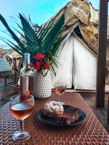 einen Tisch mit einem Teller Essen und zwei Gläsern Wein in der Unterkunft Kawaida - Hébergement insolite - Glamping Makazi in Sainte-Luce