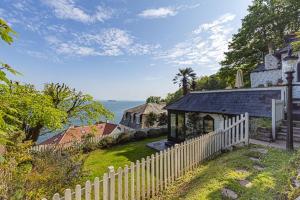 a white fence in front of a house with the ocean at 3 Bed - Smugglers Cottage in Torquay