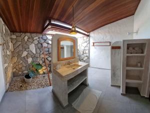 uma casa de banho com um lavatório e uma parede de pedra em Chalés Bayern em Icaraí