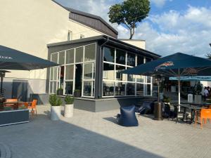 a building with tables and umbrellas in front of it at Bohema in Telšiai