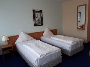 two beds in a hotel room with a mirror at Hotel Am Flughafen in Cologne