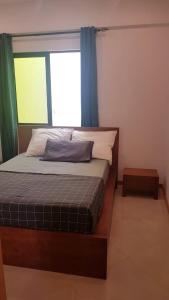 a bedroom with a bed and a window with blue curtains at Casa JPi in São Pedro