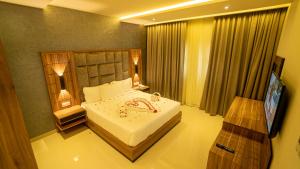 a bedroom with a large white bed and a television at The Plaza Hotel & Resort in Salalah