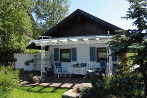 a white house with a table and chairs in a yard at Schöne Ferienwohnung im Nationalpark nördlicher Schwarzwald in Forbach +9 photos