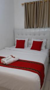 a large white bed with two red pillows on it at House of A Syariah Sukarame in Tanjungkarang +22 photos