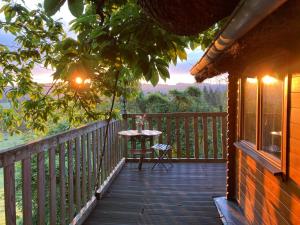 a wooden porch with a table and a table on it at Le Jardin Ecolodge in Lamarque-Pontacq