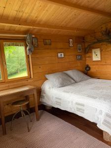 a bedroom with a bed and a table and a window at Le Jardin Ecolodge in Lamarque-Pontacq