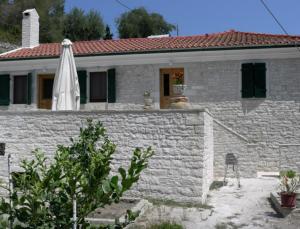 Biały kamienny dom z białym parasolem w obiekcie Villa Ermis w mieście Lákka