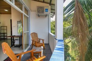 a porch with two wooden chairs and a table at FEEL Villa in Kalutara