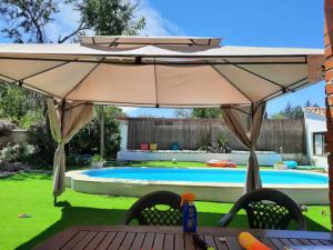 Pelayos de la Presa的住宿－Casa Rural con Piscina y AA en Sierra Oeste de Madrid，后院的大伞,带游泳池