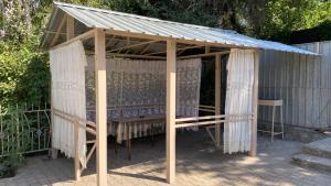 a wooden gazebo with a roof and curtains at Dimm Отель in Almaty