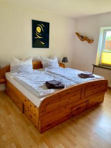 Un dormitorio con una gran cama de madera con sábanas blancas. en Güneitzblick en Clenze