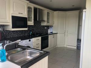uma cozinha com armários brancos e um lavatório de aço inoxidável em Centrally located coastal townhouse Belmullet em Belmullet