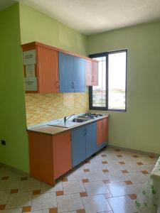 an empty kitchen with blue cabinets and a window at Festim hotel in Durrës