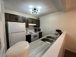 a kitchen with a white refrigerator and a sink at Nakiska, 2 Bed 1 Bath with Mtn Views in Canmore