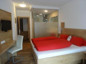 ein Schlafzimmer mit einem Bett mit roten Kissen und einem Stuhl in der Unterkunft Appartementhaus Naturquell in Sankt Leonhard im Pitztal