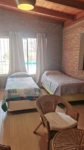 1 dormitorio con 2 camas, silla y ventana en Cabaña Solares en La Silleta