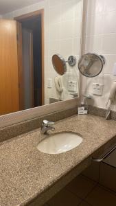 a bathroom counter with a sink and a mirror at Apartamento no condomínio do Brasil 21 Suites in Brasilia