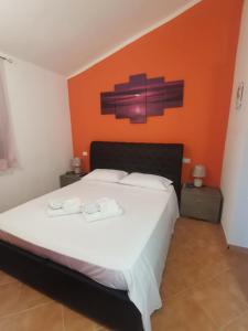 um quarto com uma cama branca e uma parede laranja em Sardegna Holiday house em Santa Maria