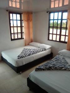 - 2 lits dans une chambre avec 2 fenêtres dans l'établissement Finca Hotel La Marina, à Quimbaya