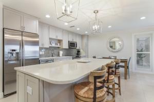 a kitchen with white cabinets and a large island with bar stools at Waters Edge 104S condo in Holmes Beach +24 photos