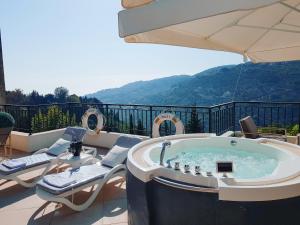 a hot tub on a patio with chairs and an umbrella at Beit Lebbos Boutique Hotel in Beït ed Dîne