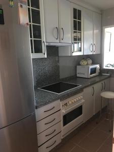 kuchnia z białymi szafkami i piekarnikiem w obiekcie HUELVA PLAYAS DEL SUR w mieście El Portil