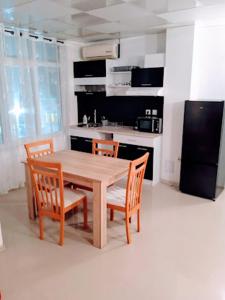a kitchen with a wooden table with chairs and a refrigerator at VIP apart SVETLANA in Ravda