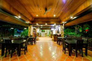 um restaurante com mesas, cadeiras e plantas em Pai Tan Villas - SHA Extra Plus em Bang Tao Beach