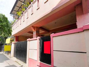 SPOT ON 91367 Rumah Bundo Syariah في باندونغ: مبنى وردي وبيض مع بوابة