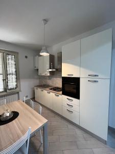 a kitchen with white cabinets and a wooden table at La Casa sul Duomo in Terni